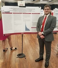Picture of student presenting research poster at conference